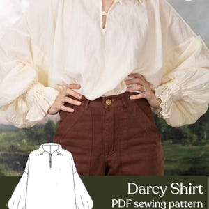 May include: Cream-colored Darcy shirt with a relaxed fit and voluminous sleeves. The shirt features a notched neckline and is paired with brown pants. The image includes a line drawing of the shirt and text that reads "Darcy Shirt PDF sewing pattern Unisex S-5X Difficulty: Confident Beginner."