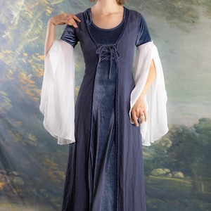 May include: A long, navy blue dress with a velvet bodice and a lace-up front. The dress features long, flowing white sleeves. The dress is floor-length and has a medieval or renaissance style.