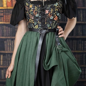 A black and green dress with a floral print bodice and a long, flowing skirt. The dress has a lace-up bodice and a belt with a buckle and skirt hikes