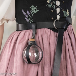 Potion bottle holder attached to black leather belt against floral corset and dusty pink renaissance skirt