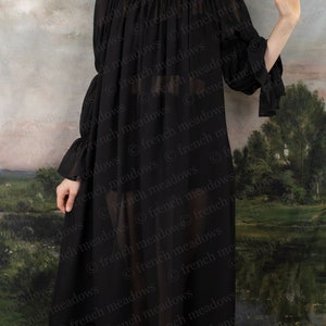 Black Chiffon Long Sleeve Chemise shown off-shoulder with flowing fabric against pastoral backdrop, showcasing sheer elegant design