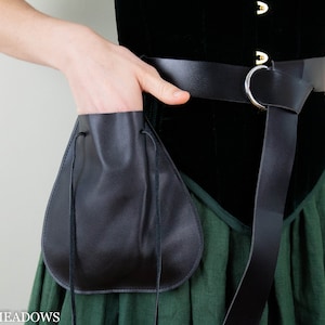 Black drawstring pouch attached to leather belt, shown against green skirt and black velvet top in medieval costume style