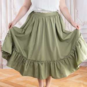 May include: A light green skirt with a ruffled hem. The skirt is paired with a white top. The skirt is a flowing, full length design.