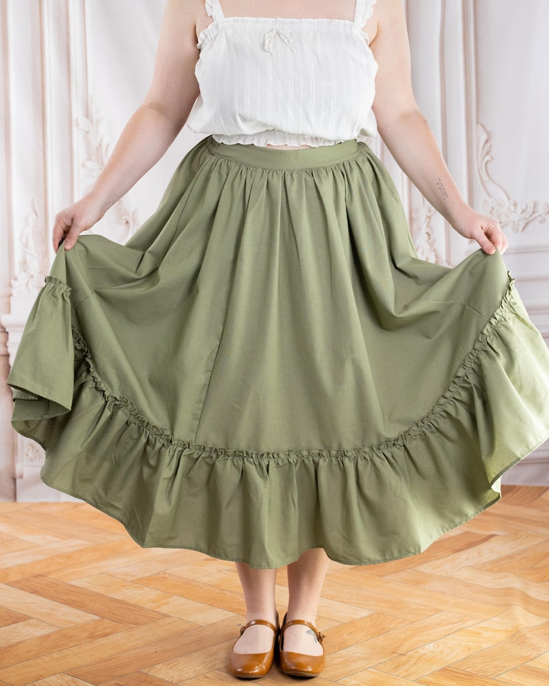 May include: A light green skirt with a ruffled hem. The skirt is paired with a white top. The skirt is a flowing, full length design.