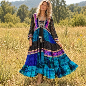 May include: A long-sleeved duster coat featuring a vibrant patchwork design in shades of blue, black, and purple. The garment includes intricate lace detailing, velvet panels, and a ruffled hemline, creating a layered, flowing silhouette.