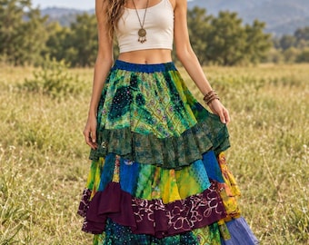 May include: A beige sleeveless crop top paired with a long, tiered maxi skirt featuring a patchwork design of green, blue, yellow, and purple fabrics with various patterns, including floral and geometric prints, and a ruffled hemline.