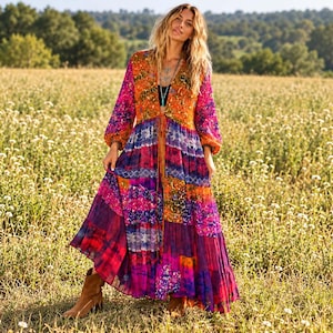 May include: A long-sleeved maxi dress featuring a vibrant patchwork design with shades of orange, purple, pink, and blue. The dress has a deep V-neckline, a front tie closure, and a flowing, tiered skirt that reaches the ankles.