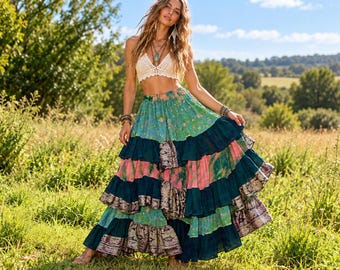 May include: A cream-coloured crochet crop top paired with a long, tiered maxi skirt featuring alternating panels of floral green, solid dark teal, and pink fabric with a decorative metallic-toned patterned border at the hem.