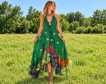 May include: A floor-length green dress featuring a deep V-neckline, thin straps, and a multi-layered skirt with tie-dye patterns in blue, yellow, and orange. The bodice and skirt are adorned with small, circular floral-shaped embellishments.