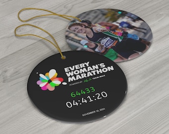 May include: Two round black ornaments with gold string loops. One features a marathon runner image, the other has text: "EVERY WOMAN'S MARATHON" with a colorful flower logo, race number, and time. The date "NOVEMBER 16, 2024" is also printed.