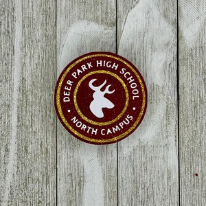 K&ouml;nnte beinhalten: Ein runder Aufkleber in Rot und Gold mit dem Text "Deer Park High School North Campus" und einer wei&szlig;en Silhouette eines Hirschkopfes.