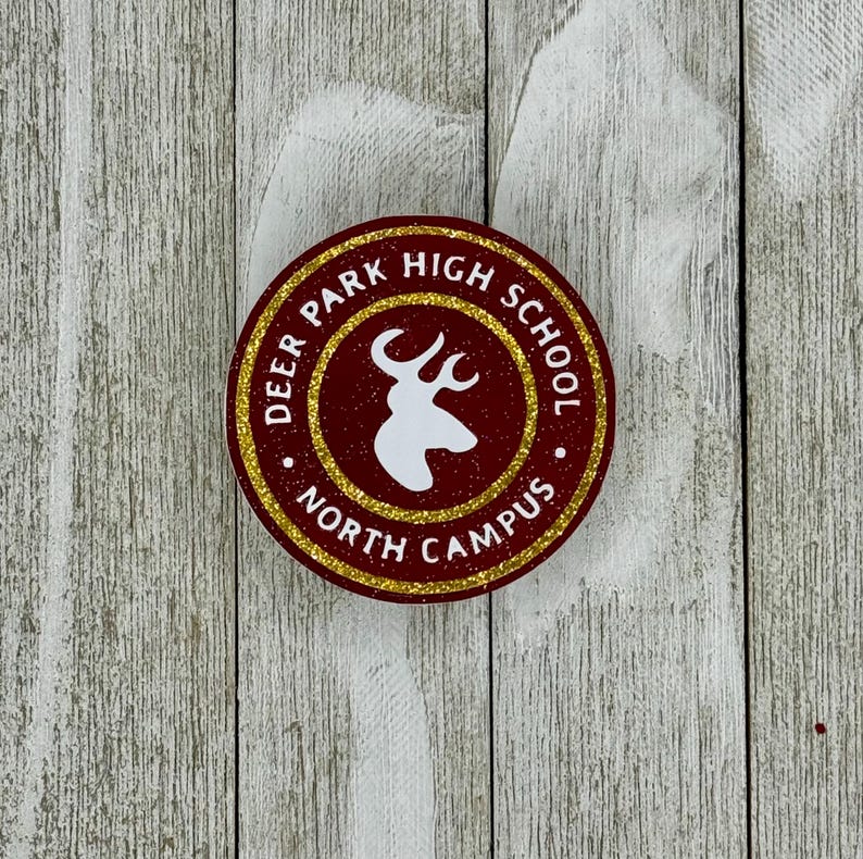 K&ouml;nnte beinhalten: Ein runder Aufkleber in Rot und Gold mit dem Text "Deer Park High School North Campus" und einer wei&szlig;en Silhouette eines Hirschkopfes.