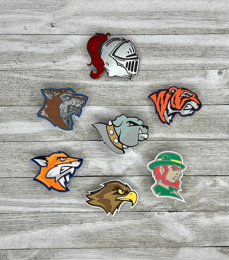 K&ouml;nnte beinhalten: Sieben bunte B&uuml;gelbilder mit verschiedenen Tier- und Maskottchen-Designs. Die Patches zeigen einen Ritter, einen Wolf, eine Bulldogge, einen Fuchs, einen Adler, einen Tiger und einen Kobold.