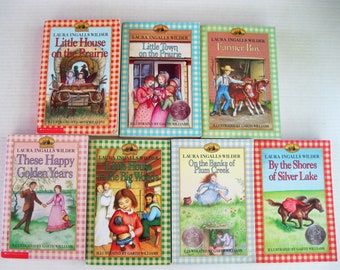 May include: A set of eight Little House on the Prairie books by Laura Ingalls Wilder. The books are illustrated by Garth Williams and feature colorful covers with scenes from the stories.