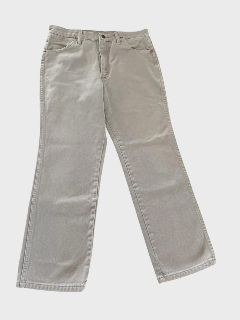 Op de afbeelding: Een lichtgrijze spijkerbroek. De jeans heeft een klassiek ontwerp met vijf zakken, een knoop- en ritssluiting en riemlussen. De jeans heeft een neutrale kleur en is geschikt voor diverse outfits.