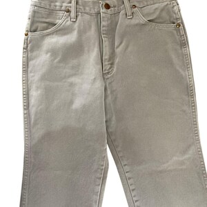 Op de afbeelding: Een lichtgrijze spijkerbroek. De jeans heeft een klassiek ontwerp met vijf zakken en een knoop- en ritssluiting. De jeans is gemaakt van duurzaam denim materiaal en heeft een rechte pijp.