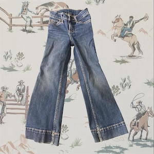 Op de afbeelding: Een blauwe spijkerbroek met uitlopende pijpen, een klassiek ontwerp met vijf zakken, een knoop- en ritssluiting, zichtbare stiksels langs de naden en een vervaagde wassing aan de voorzijde van de broekspijpen.