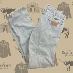 Pu&ograve; includere: Jeans in denim azzurro con taglio a gamba dritta, design classico a cinque tasche, etichetta in pelle marrone sulla tasca posteriore con logo Wrangler, rivetti color rame e una caratteristica cucitura a forma di W sulla tasca posteriore.
