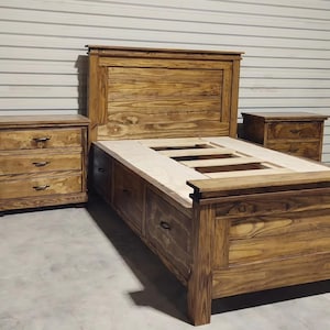 May include: A wooden bedroom set featuring a bed frame with storage drawers, a headboard, and two matching nightstands. The furniture is made of stained wood with visible grain, and each nightstand has three drawers. The bed frame has a platform base.