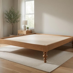 May include: A low-profile wooden bed frame featuring a light oak finish and a flat platform surface. The frame is supported by four distinctively turned, spool-style legs at each corner, providing a stable base for a mattress in a bedroom setting.