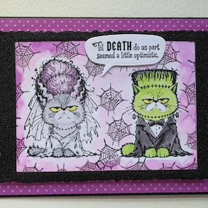 May include: A rectangular greeting card featuring a purple background with white polka dots and a black scalloped border. The center illustration shows two cats dressed as Frankenstein's monster and bride, with a speech bubble reading 'Til DEATH do us part seemed a little optimistic.'