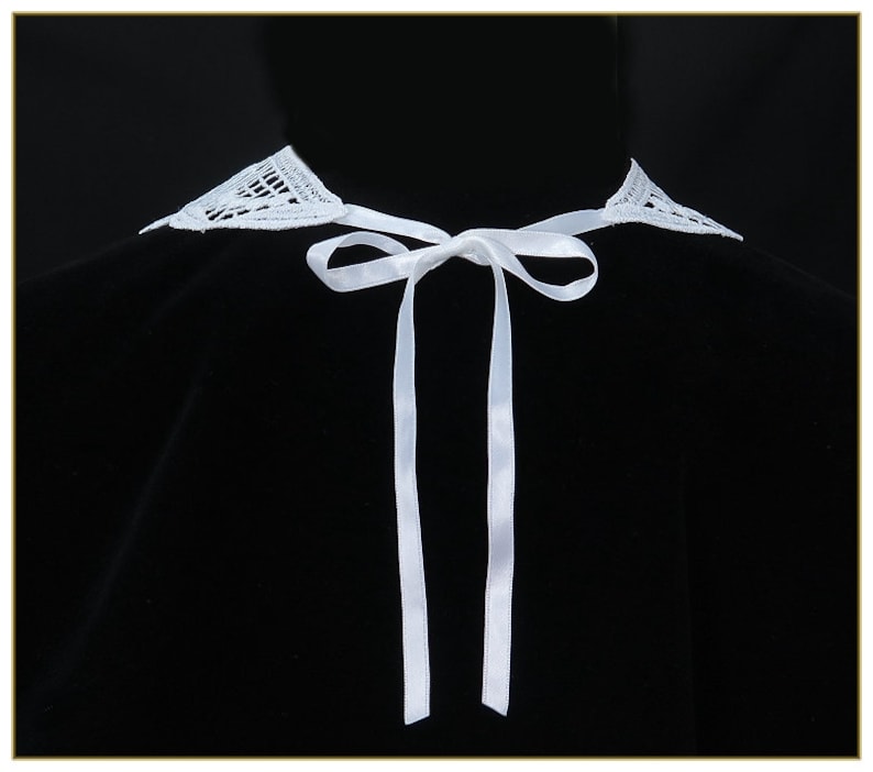 May include: A white lace collar with a white satin ribbon tie. The collar is on a black background.