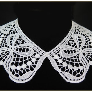May include: White lace collar with a delicate floral pattern. The collar is made of a soft, lightweight fabric and has a scalloped edge.