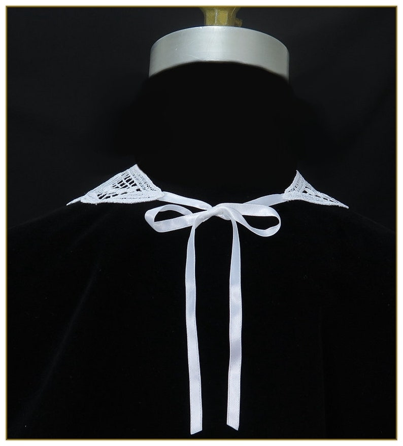May include: White lace collar with a white satin ribbon tied in a bow. The collar is on a black background.