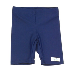 May include: Navy blue swim shorts with a white label that says "kozle" in blue letters.