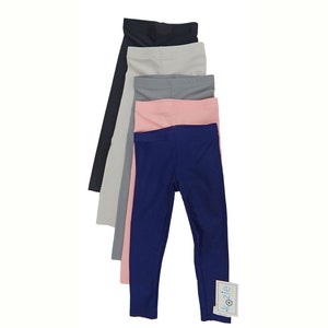 May include: Five pairs of leggings in different colors: navy blue, light gray, pink, dark gray, and black. The leggings are stacked on top of each other. The bottom pair of leggings has a "Kozie" tag attached.