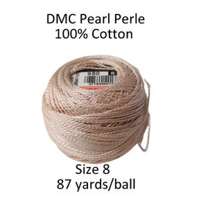 May include: A ball of DMC Pearl Perle thread in a light beige color. The label indicates it is 100% cotton, size 8, and contains 87 yards per ball. The text "DMC Pearl Perle" and "100% Cotton" are visible.