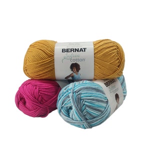 May include: Three skeins of yarn in yellow, pink, and blue and white stripes. The yarn is labeled "Bernat Softee Cotton".