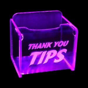 May include: A clear acrylic tip jar with a purple glow. The jar has the words "Thank You Tips" etched into the front.