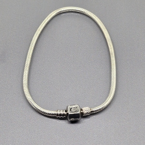 Può includere: Un braccialetto a catena di serpente d'argento con un ciondolo d'argento con la lettera "C".