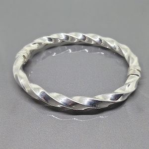 May include: A silver twisted bangle bracelet with a hinged clasp.