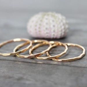 Pode incluir: Quatro an&eacute;is de ouro martelado empilh&aacute;veis. Os an&eacute;is s&atilde;o simples e delicados, com um acabamento texturizado.