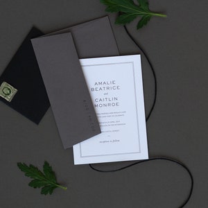 Peut inclure: Ensemble de faire-part de mariage comprenant une carte blanche avec bordure grise, une enveloppe grise et une enveloppe noire avec un timbre vert. L'invitation comprend les noms Amalie Beatrice et Caitlin Monroe. Des feuilles vertes et une ficelle noire sont incluses.