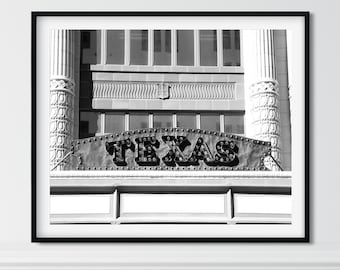 May include: Black and white photograph of a building with a sign that reads "TEXAS" in large, bold letters. The sign is made of metal and has a vintage look.