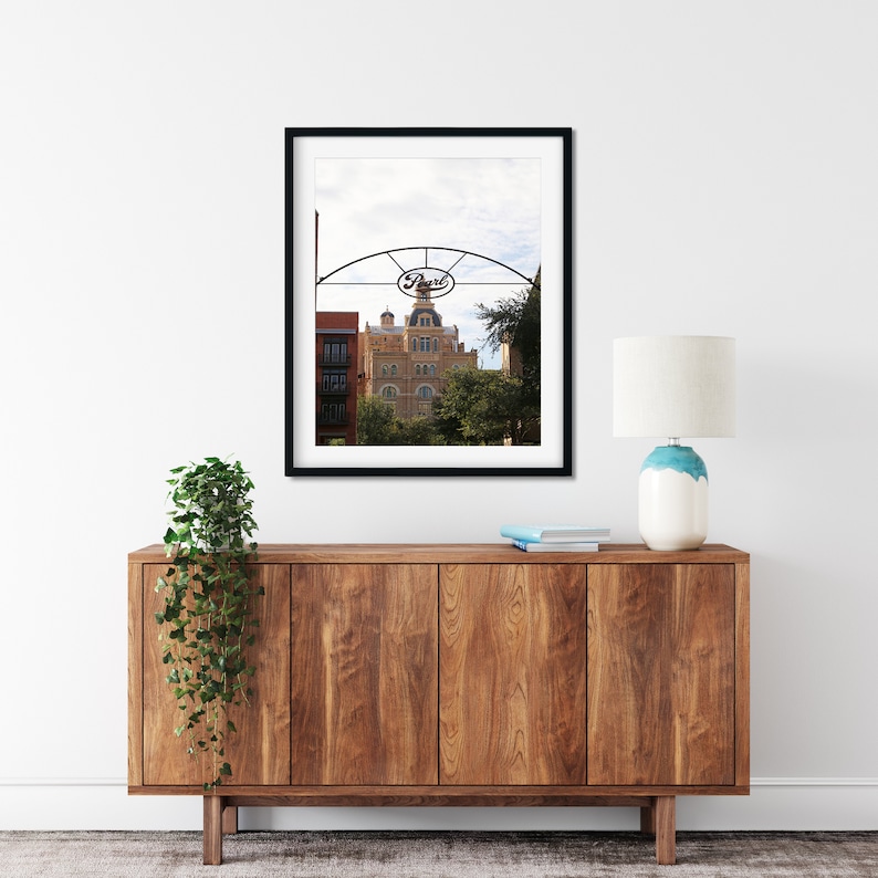 May include: A framed photograph of a building with a sign that reads "Pearl" above it. The building is a brick building with a dome on top. The photograph is in a black frame and is hanging on a white wall.