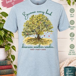 May include: A light blue heathered t-shirt featuring a graphic of a large tree with books hanging from its branches and scattered on the ground. The text reads: Because every book deserves another reader... well • read • roots.