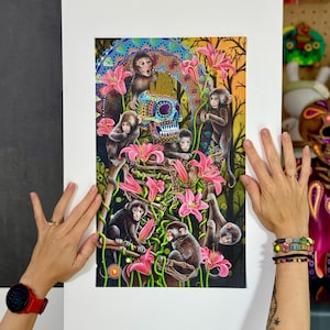 Puede incluir: Una colorida impresión artística con monos, lirios rosas y una calavera decorada. Los monos se representan en varias poses en medio de las flores y el follaje. La obra de arte tiene una paleta de colores vibrantes con un tema del Día de Muertos.