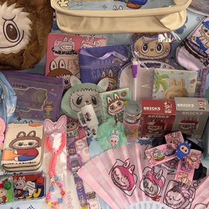 May include: A collection of various cartoon-themed merchandise, including plush toys, a backpack, pencil cases, a fan, and pens. The items feature cute character designs in pastel colors, with a light blue background.