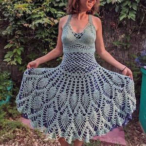 May include: A light green crochet dress with a scalloped hemline. The dress has a halter neckline and a fitted bodice.
