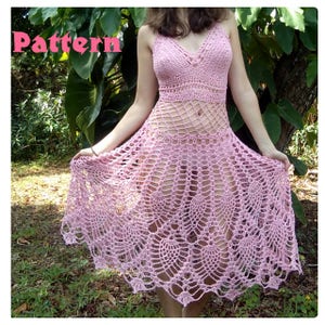 May include: A pink crochet dress with a delicate, lacy pattern. The dress has a fitted bodice and a flowing skirt.