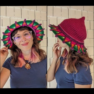 May include: A woman wearing a pink and green crocheted hat with a pointed crown and a wide brim. The hat has a colorful floral design with pink, green, orange, and yellow accents.