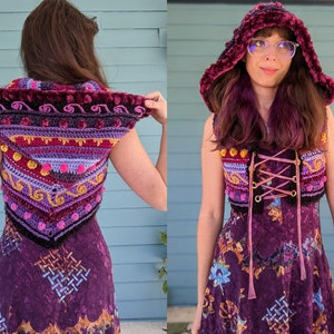 Puede incluir: Un chaleco de crochet morado con capucha, con un patrón geométrico colorido con pompones y un ribete de terciopelo negro. El chaleco se lleva sobre un vestido morado con estampado floral.