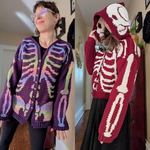 May include: Two crochet skeleton cardigans. One is a deep purple with rainbow-colored ribcage details. The other is a burgundy color with white ribcage details and a skull hood. Both have button closures.