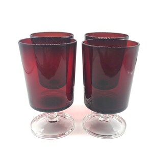 May include: Set of four red glass tumblers with clear glass stems and bases. The tumblers are a deep burgundy red color.