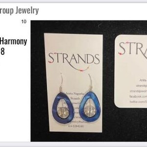 May include: Earrings with a blue teardrop design and silver accents, displayed on a white card with the word "STRANDS". The earrings are part of the "Harmony" character collection, episode 308.