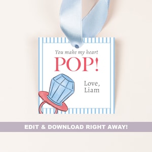 Puede incluir: Una etiqueta de regalo ilustrada azul y roja con un anillo pop y el texto "You make my heart POP! Love, Liam".